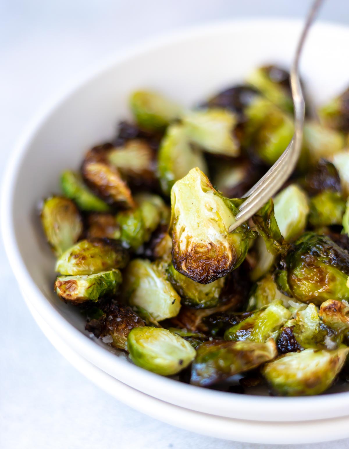 air fryer brussels sprouts in white bowl with silver fork