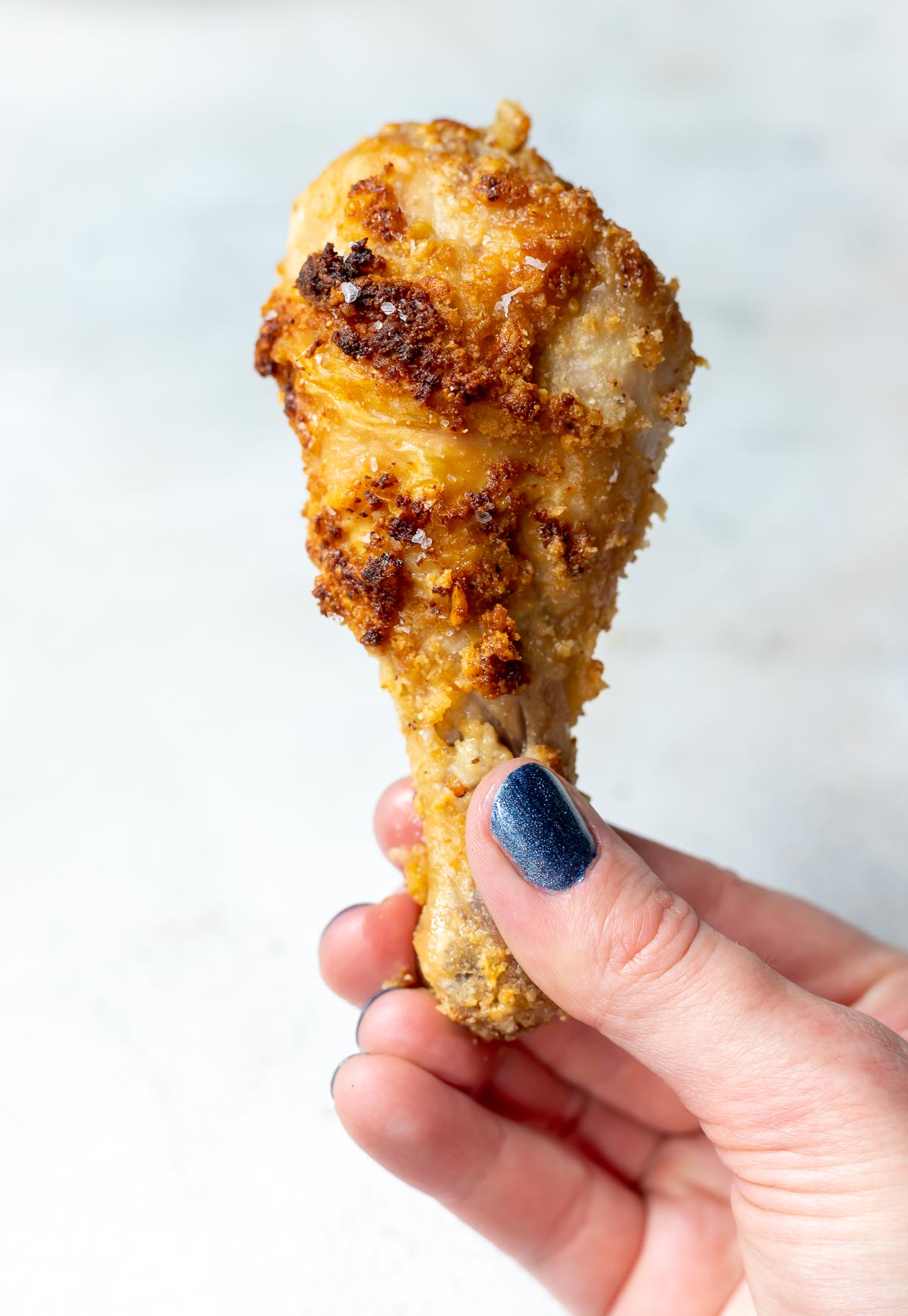 hand holding crispy keto air fryer chicken drumstick