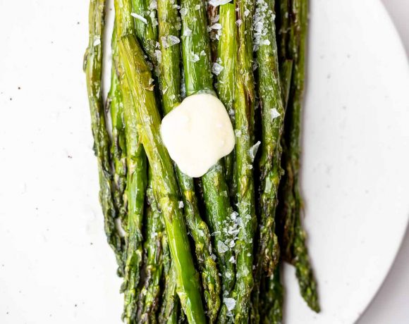 air fried asparagus on white plate, topped with salt and butter