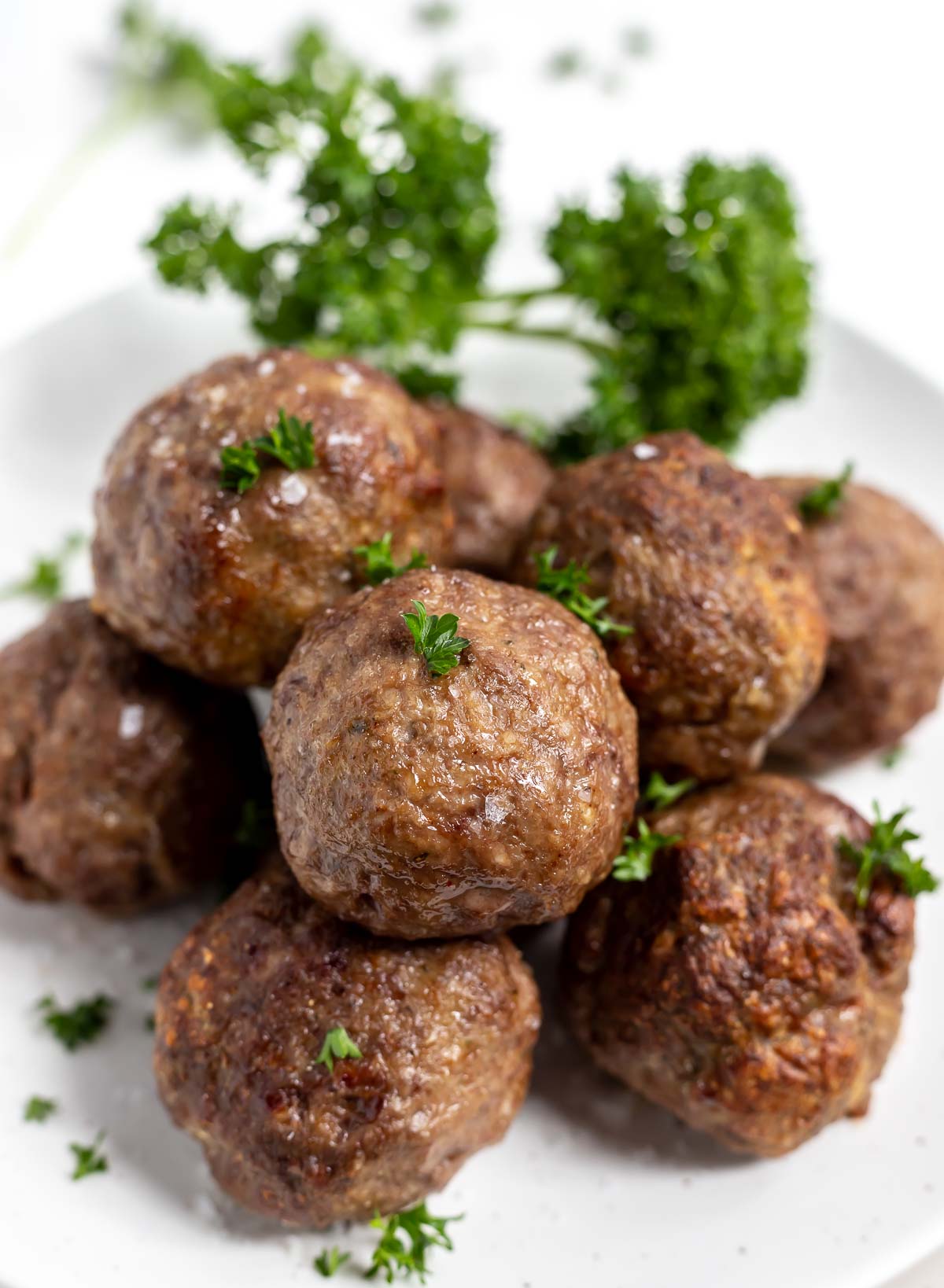 cooked meatballs on white plate with fresh green parsley