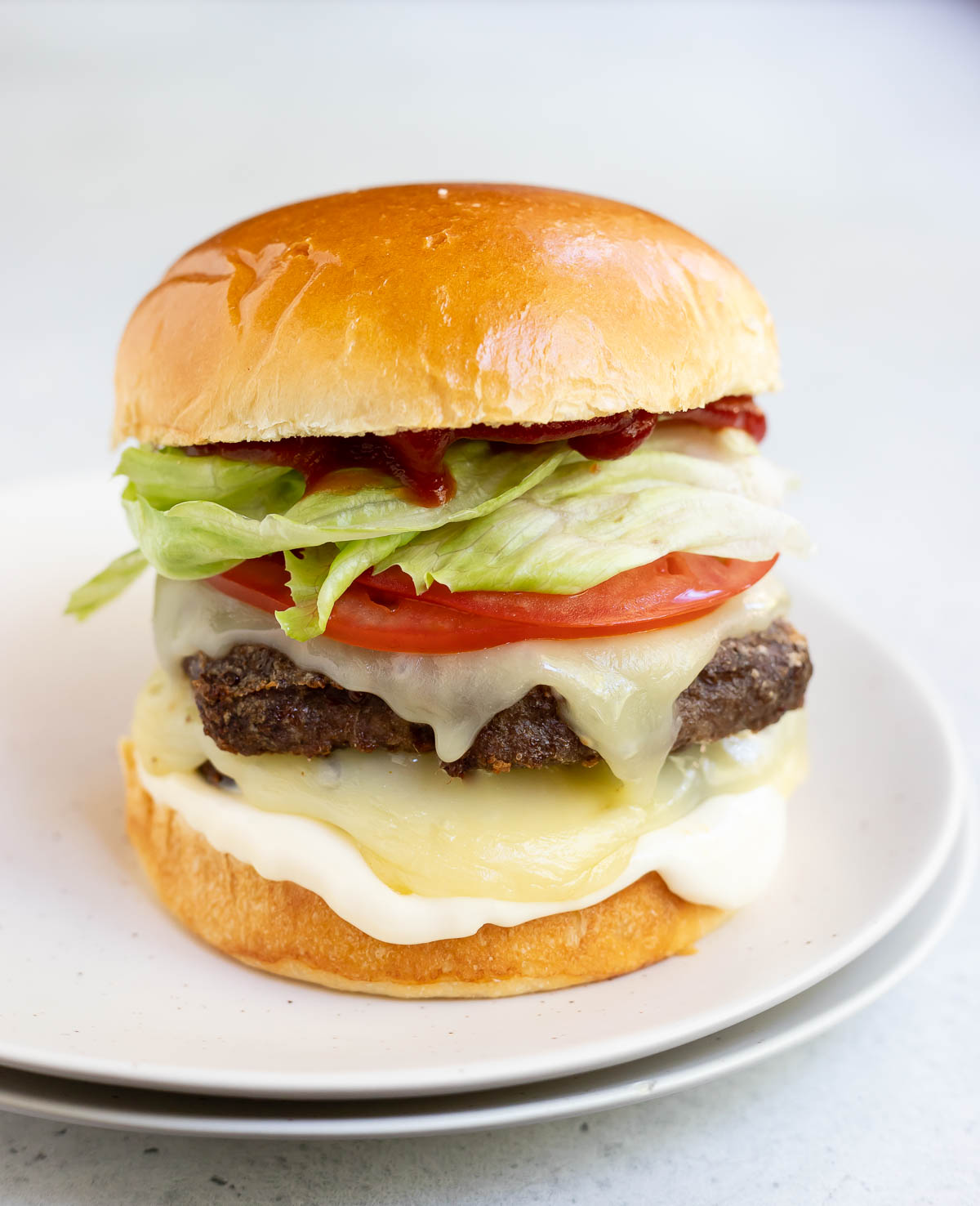 loaded cheeseburger on white plate