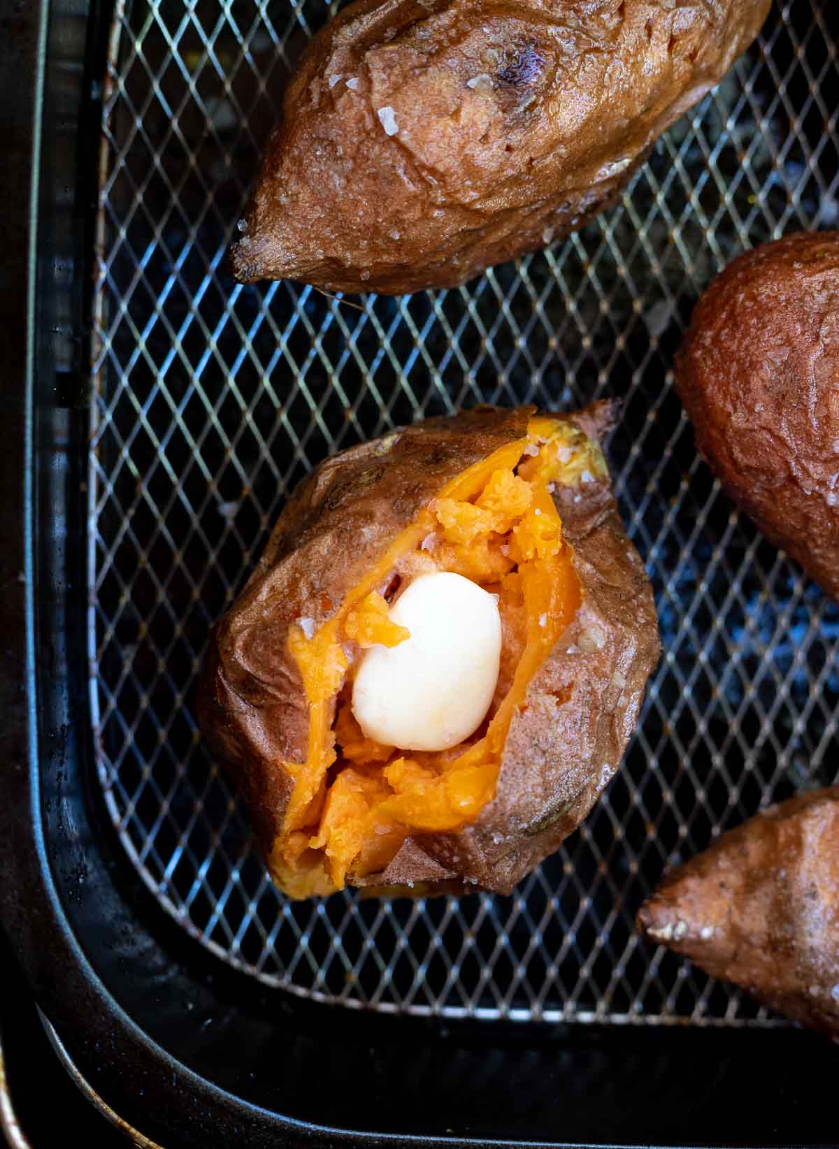 sweet potatoes filled with butter in air fryer basket 