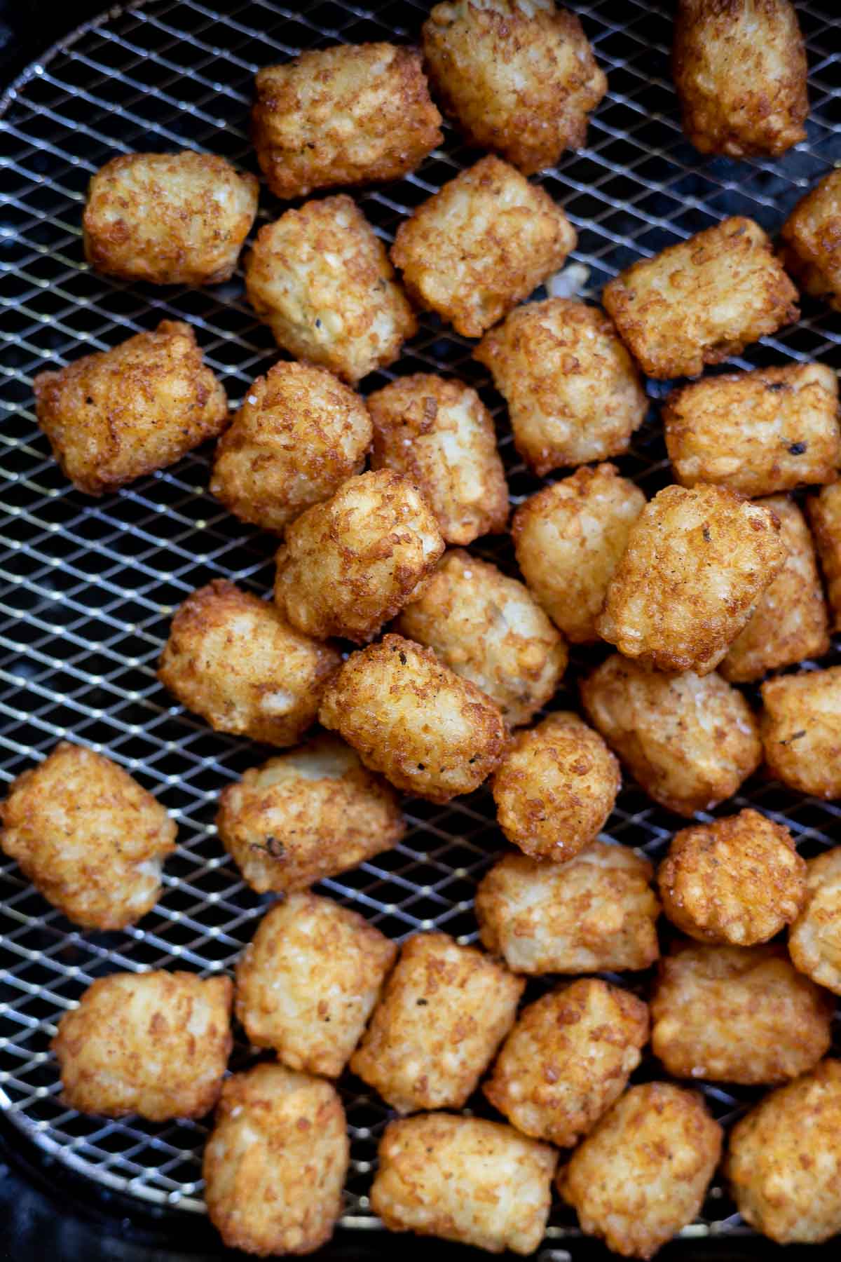golden brown cooked tater tots in air fryer basket