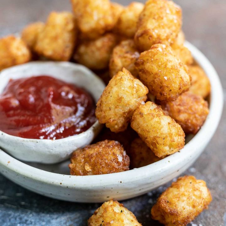 tater tots and ketchup in white dish