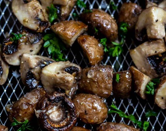 cooked mushrooms topped with parsley in air fryer basket