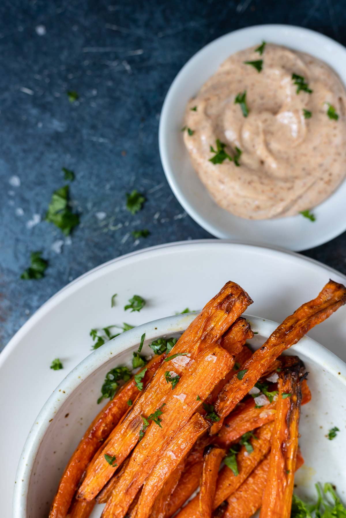 carrot fries on white plate next to creamy dip