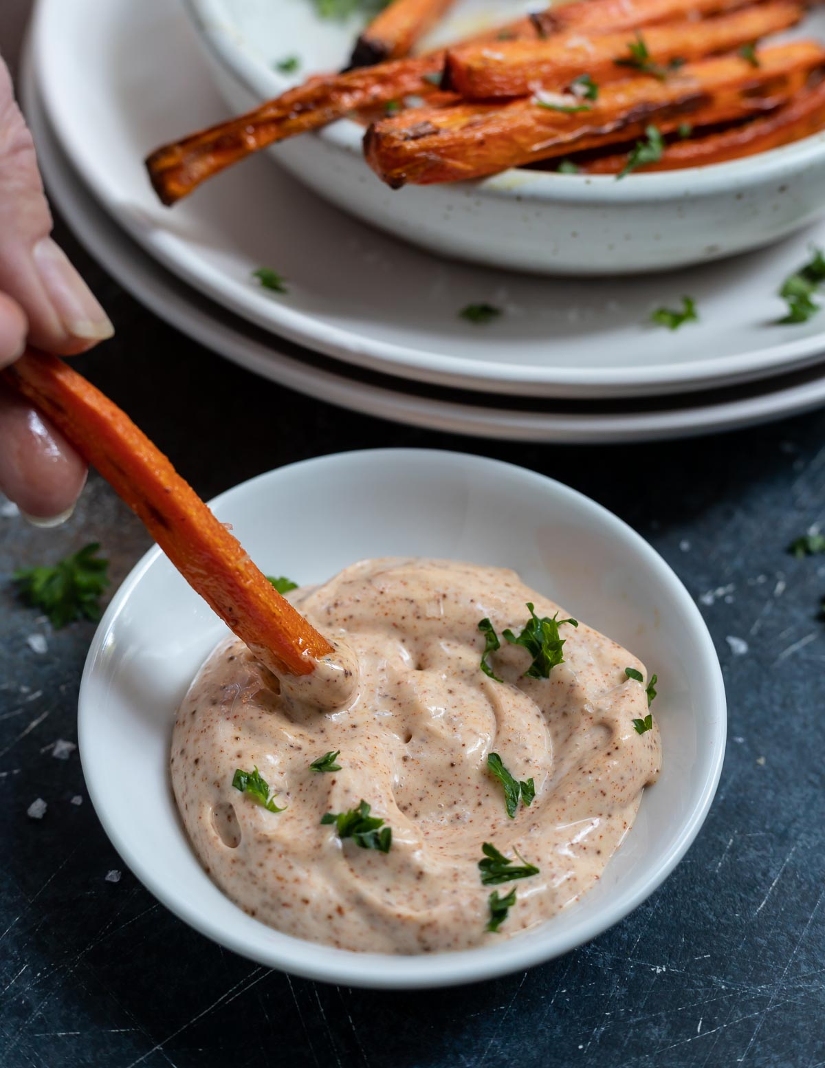 hand dipping carrot fry into dip
