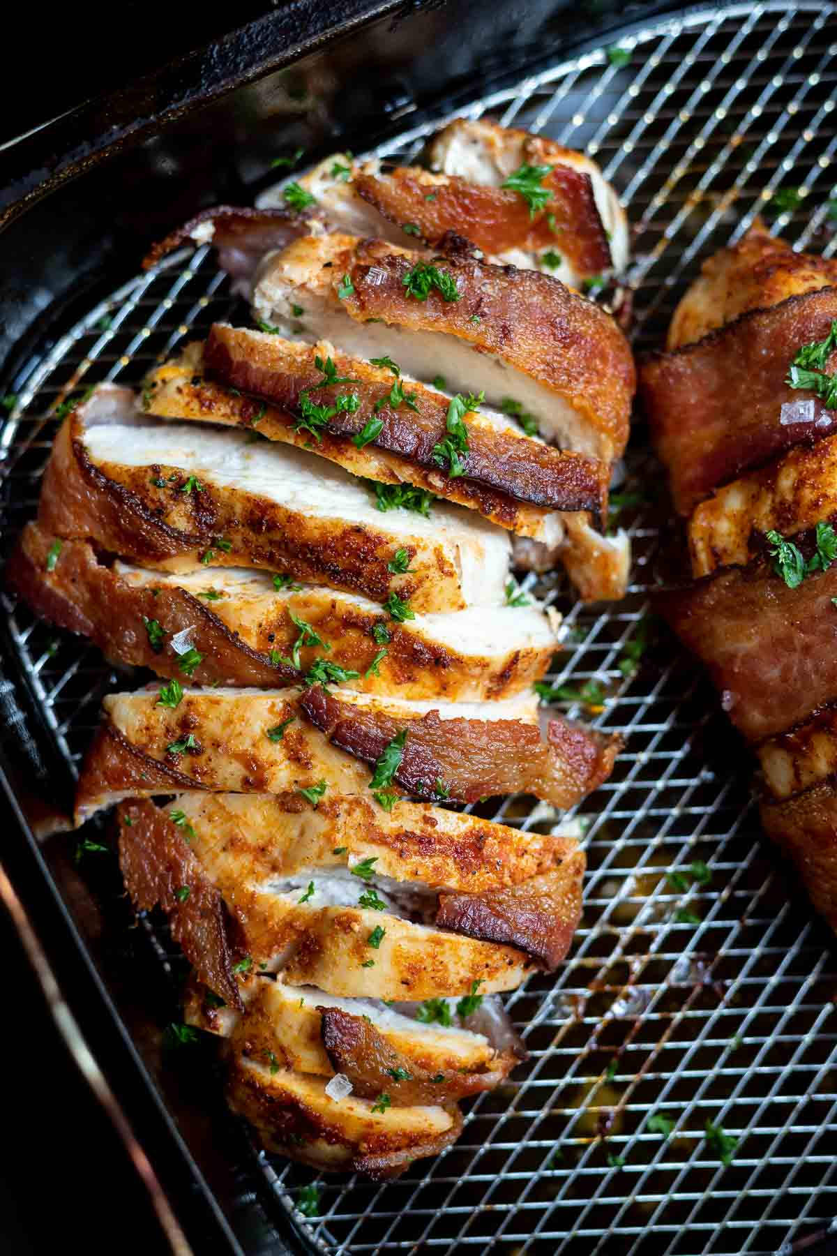 sliced bacon wrapped chicken in air fryer basket
