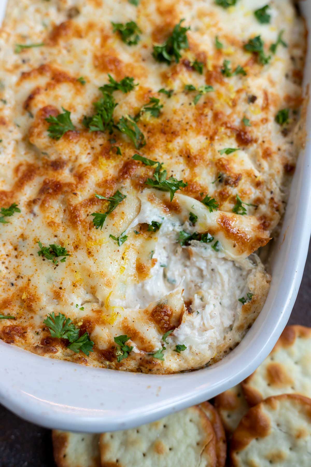 creamy crab dip topped with melted cheese and chopped parsley
