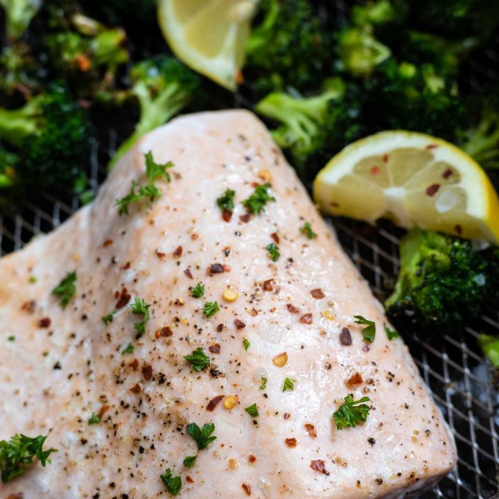 cooked salmon with broccoli and lemons in air fryer basket