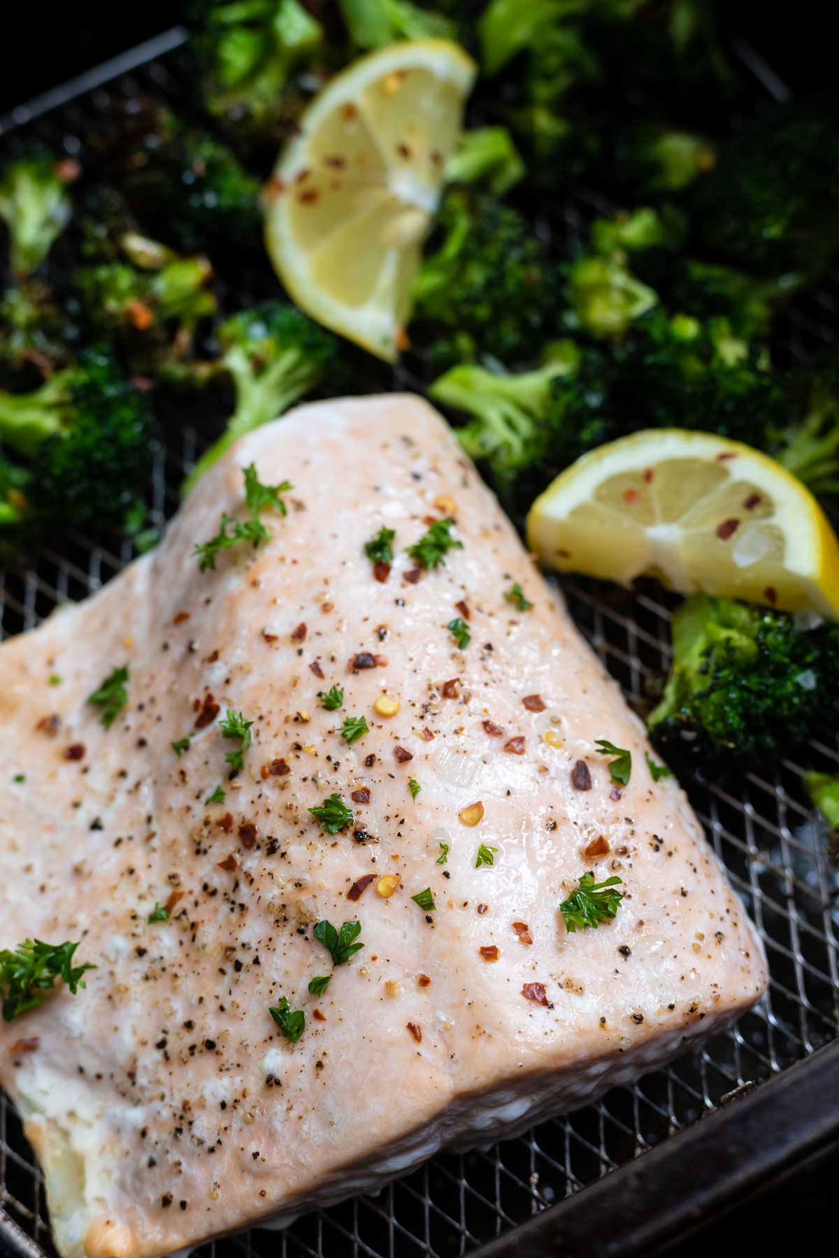 cooked salmon with broccoli and lemons in air fryer basket