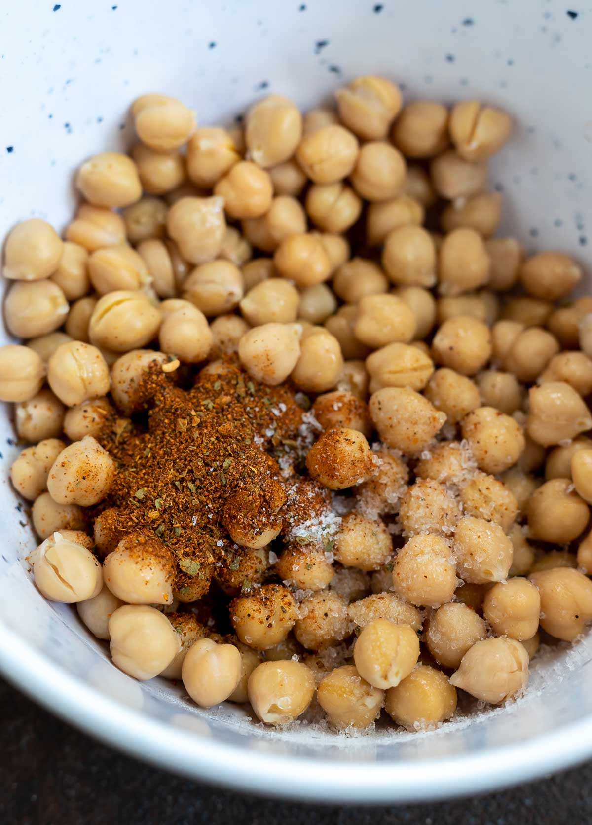 drained chickpeas and seasoning in white mixing bowl