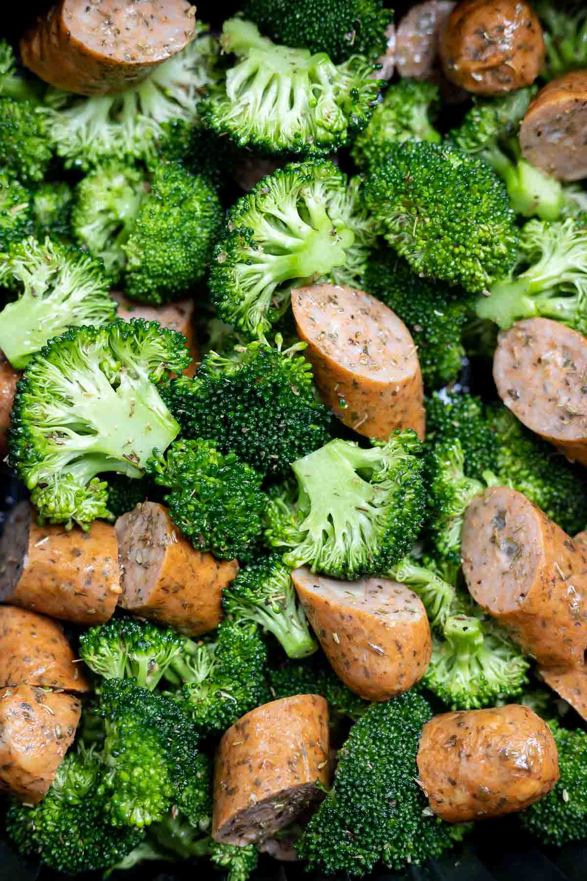 uncooked sausage and broccoli in air fryer basket