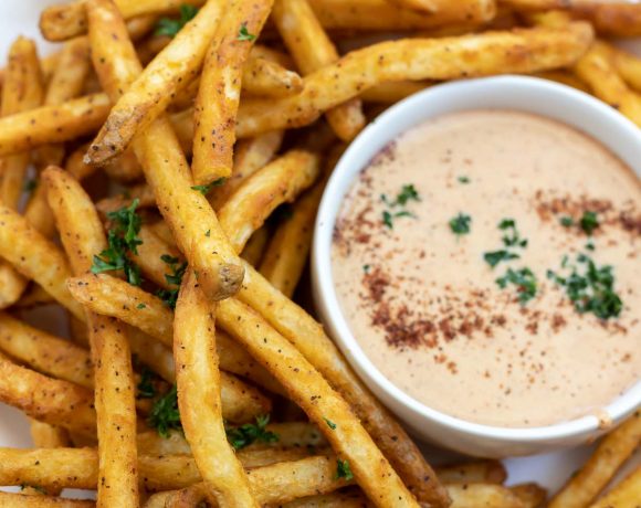 golden French fries on white plate with dipping sauce