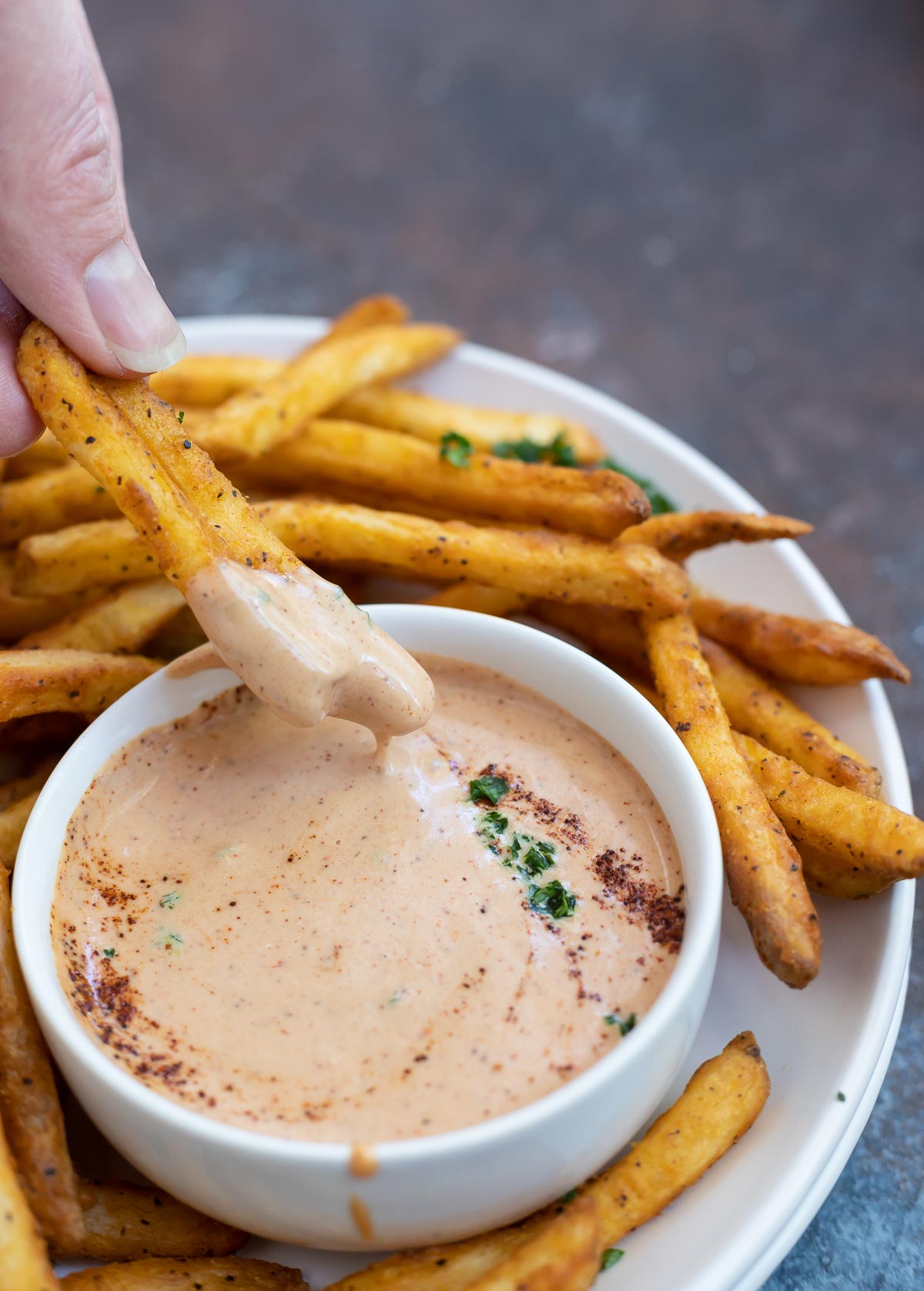 hand dipping French fries into secret sauce