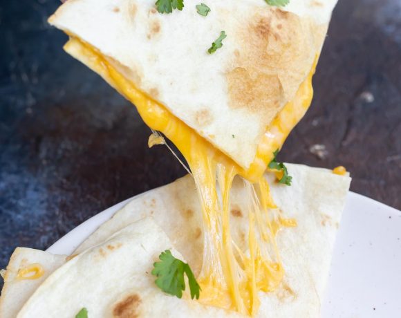hand grabbing quesadilla wedge with melty cheese stretching