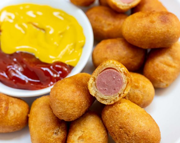 mini corndogs on white plate with dish of ketchup and mustard