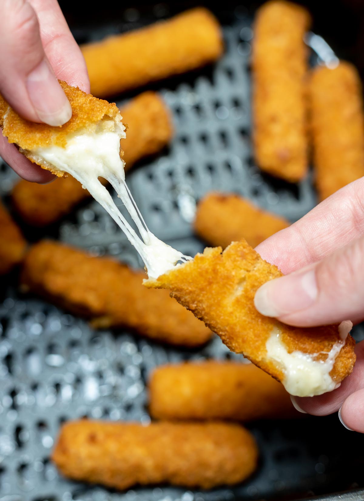 hands pulling cheese stick apart with stretchy cheese