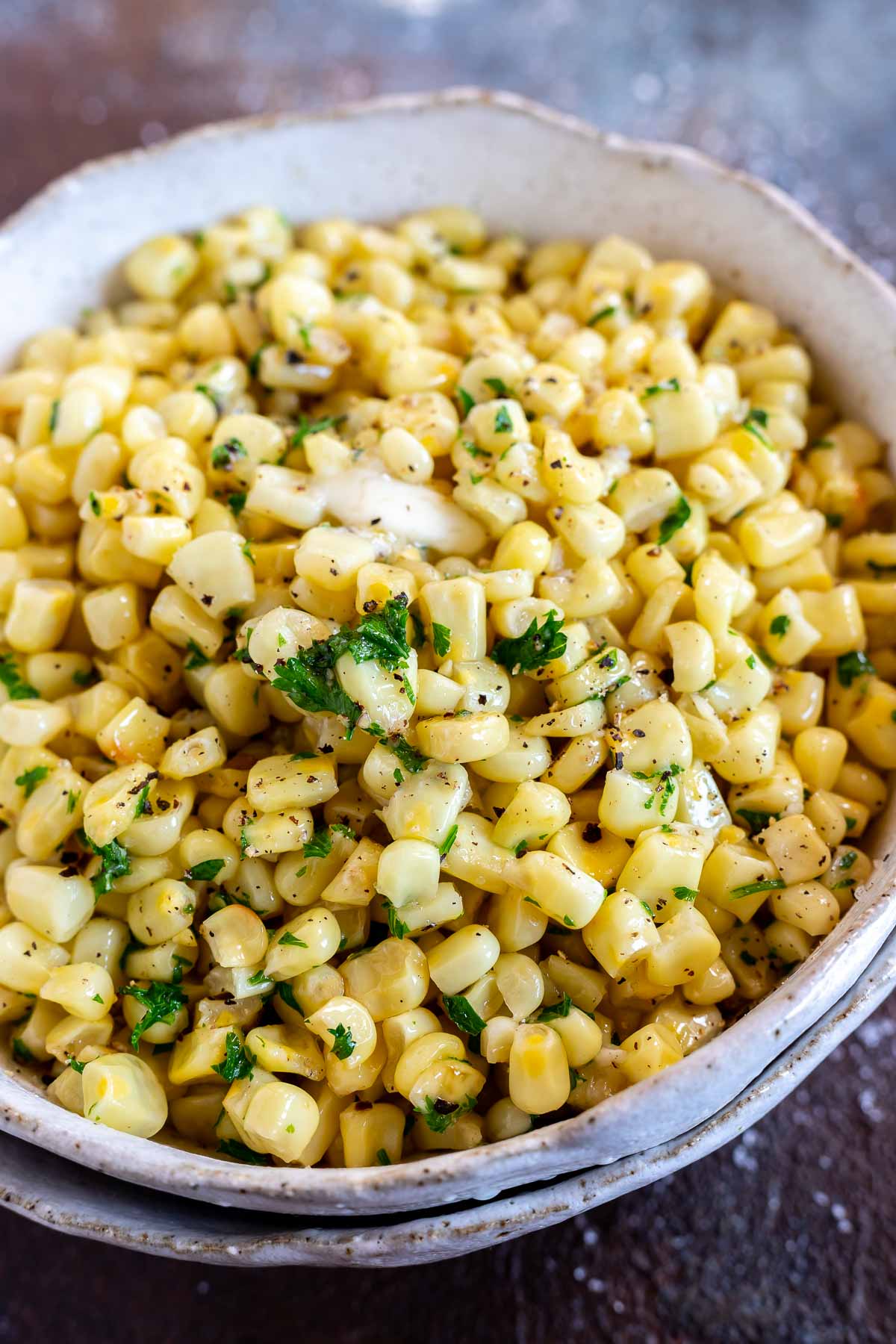 yellow corn with parsley and butter served in white bowl