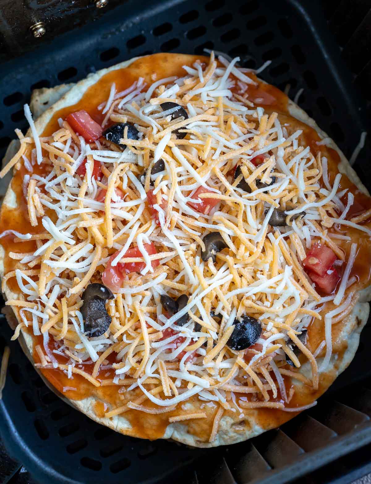 assembled uncooked Mexican pizza in air fryer basket