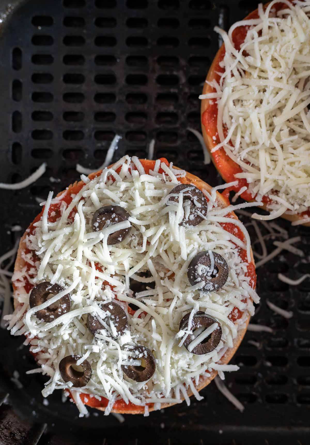 uncooked bagel pizzas in air fryer basket