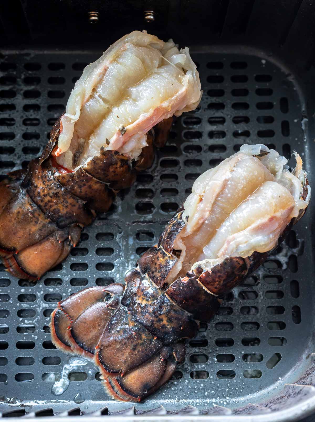 uncooked prepped lobster tails in air fryer basket