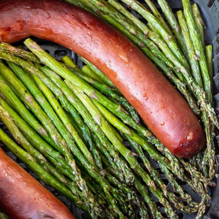 cooked sausage link and asparagus in air fryer basket