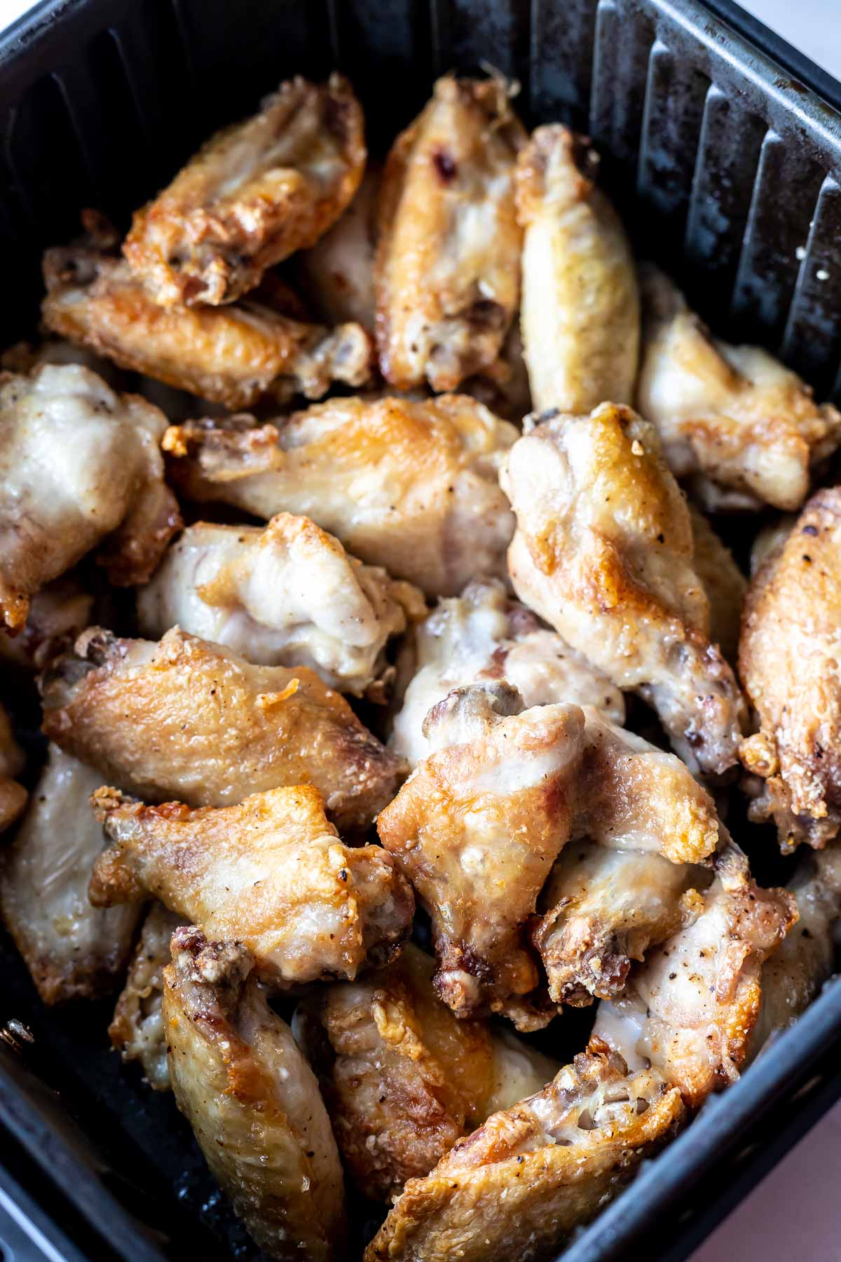 browned chicken wings in air fryer basket