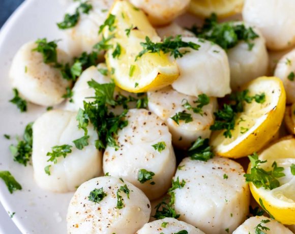 cooked scallops and lemons topped with chopped parsley served on white plate