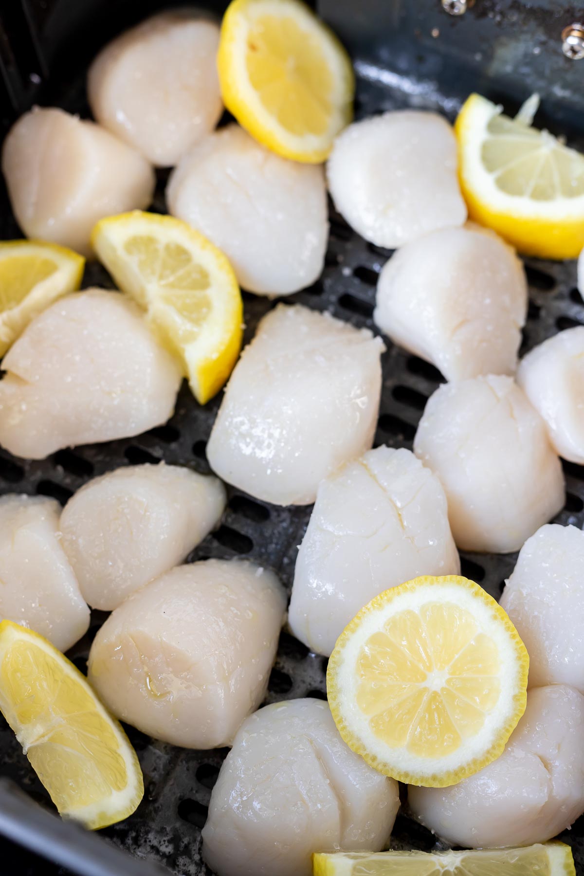 raw scallops and lemons in air fryer basket