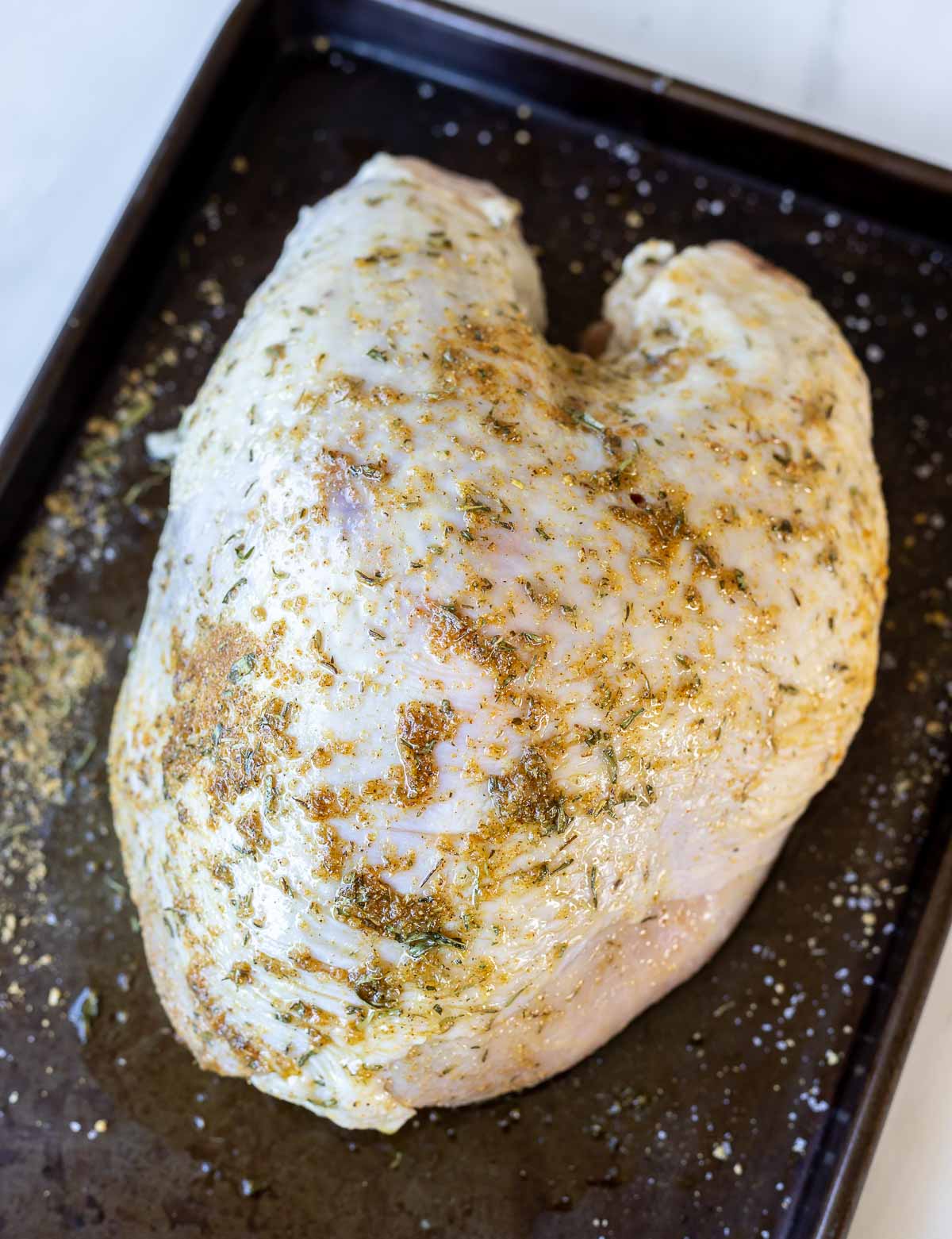 raw turkey breast coated in oil and herbs