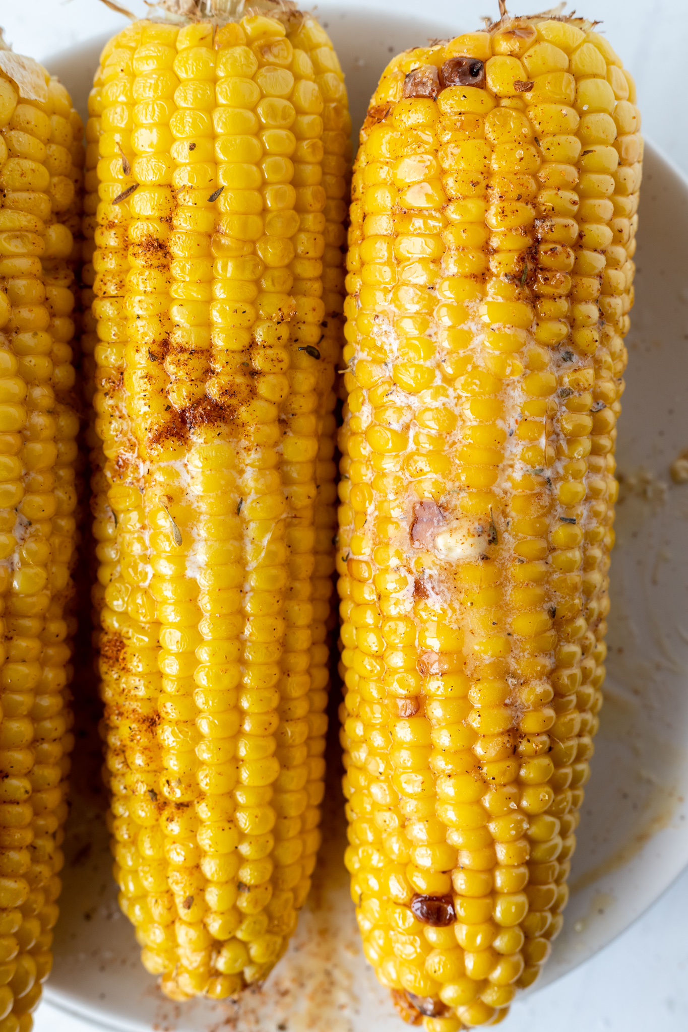 cooked buttered corn on the cob on white plate