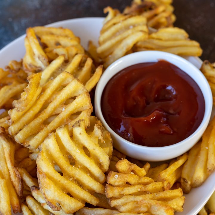 waffle fries on white plate with bowl of ketchup