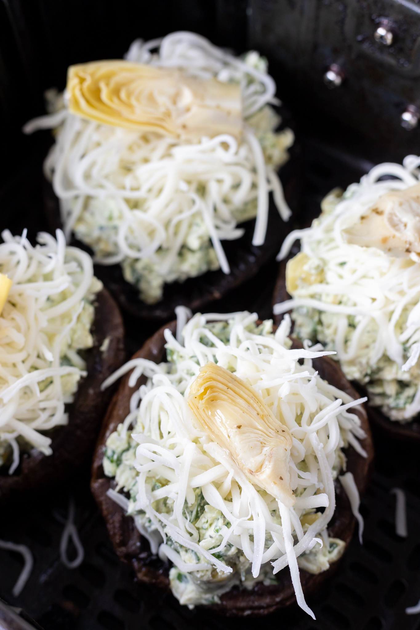 mushrooms topped with shredded cheese and artichoke heart